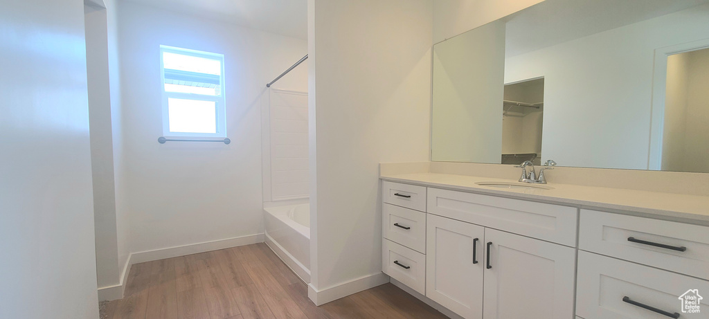 Bathroom featuring wood finished floors, vanity, baseboards, and  shower combination