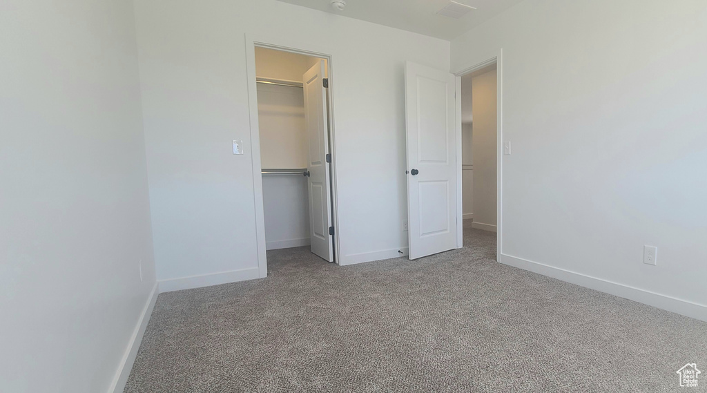 Unfurnished bedroom with a spacious closet, carpet floors, a closet, and baseboards