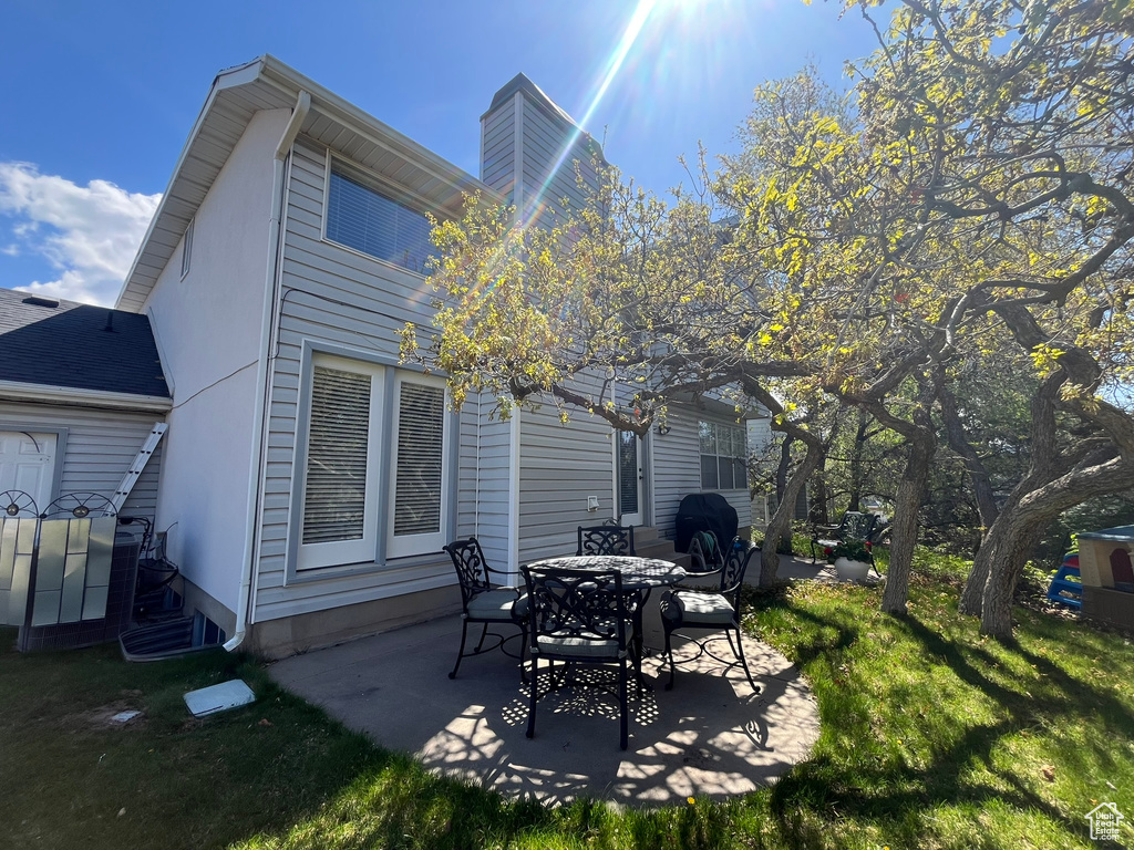 Back of house with a patio, a lawn, and a chimney