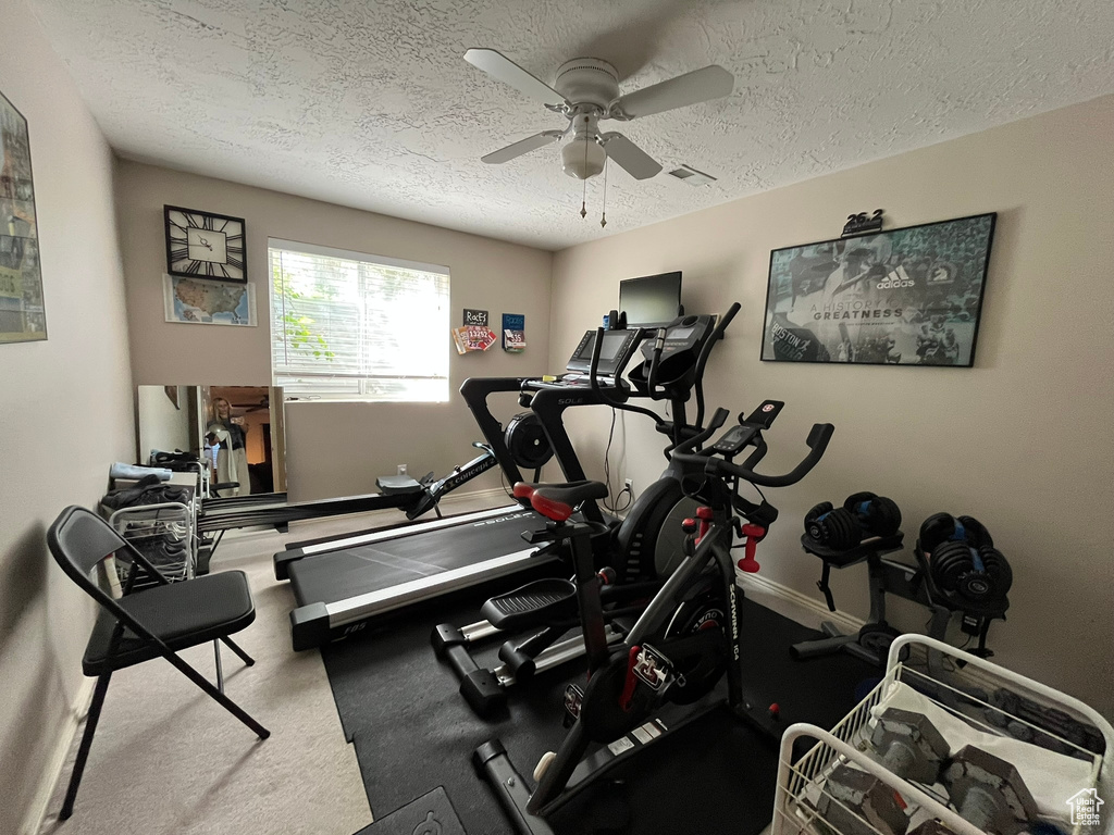 Workout area with ceiling fan, a textured ceiling, baseboards, and carpet floors