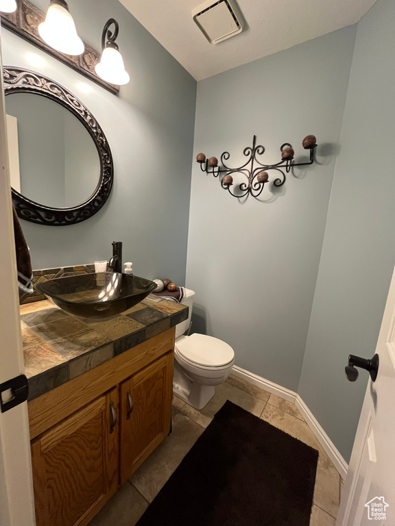 Bathroom featuring vanity, toilet, tile patterned floors, and baseboards