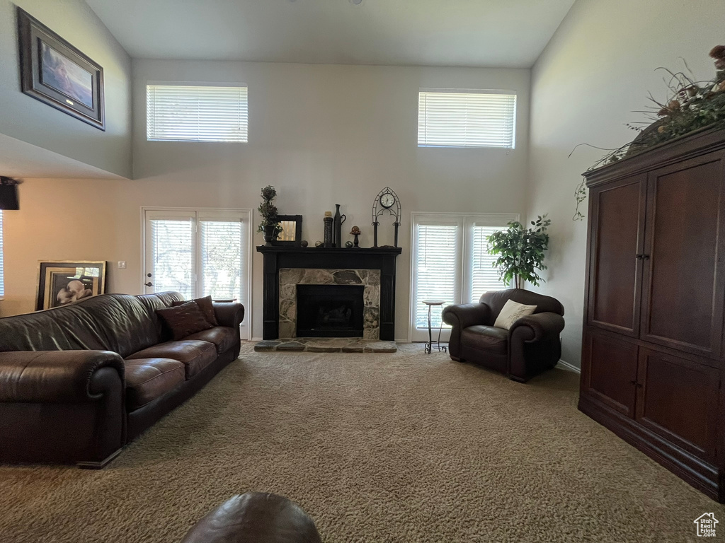 Living area with a high ceiling, carpet floors, a fireplace, and plenty of natural light