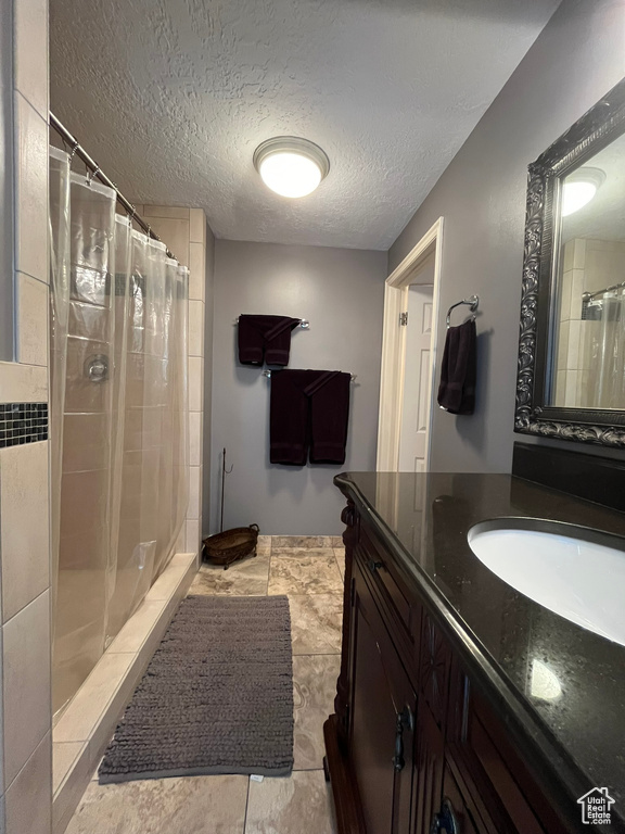 Bathroom with a shower with shower curtain, vanity, and a textured ceiling