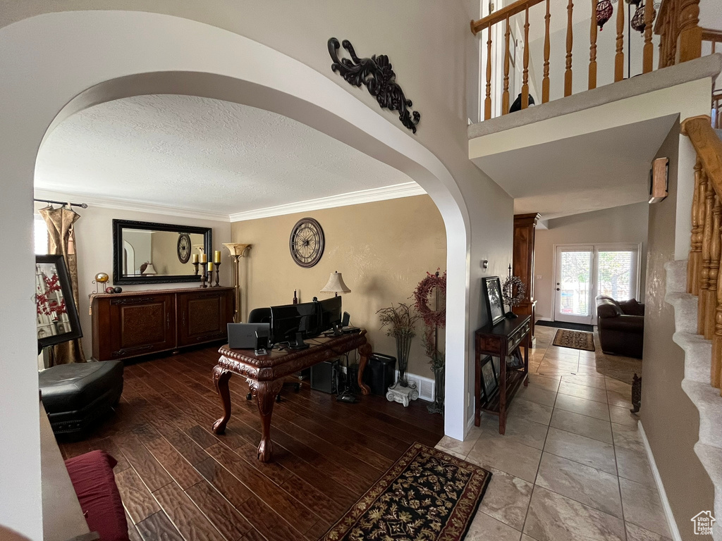 Foyer entrance featuring arched walkways, ornamental molding, a textured ceiling, and baseboards