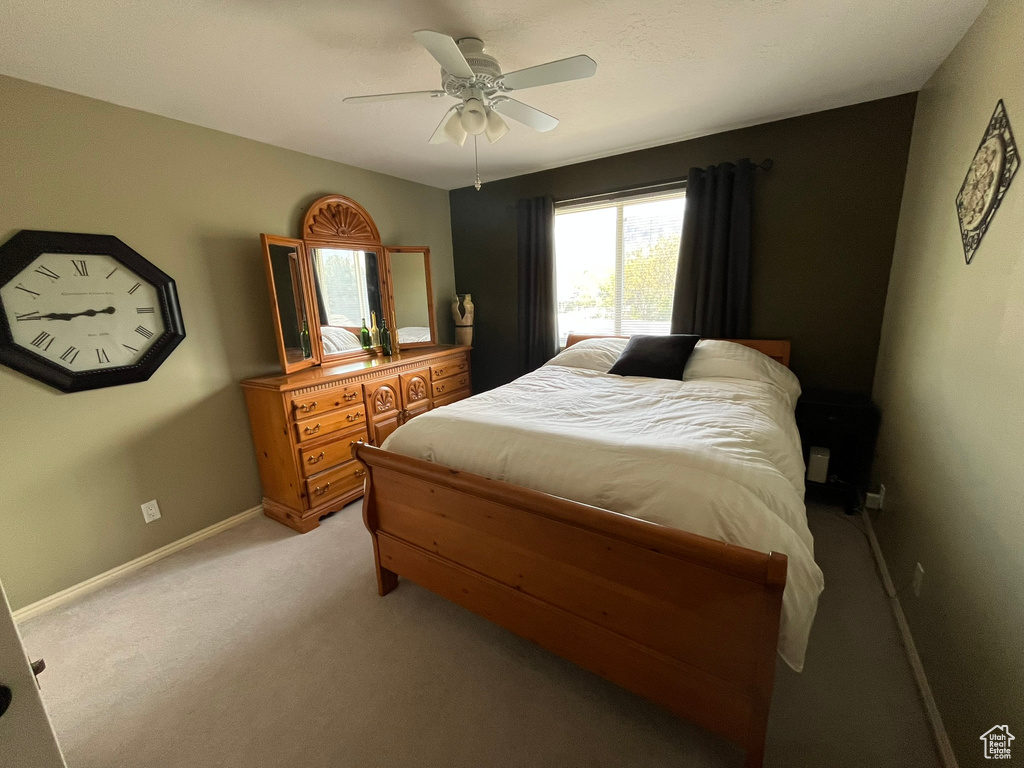 Bedroom featuring light carpet, baseboards, and ceiling fan