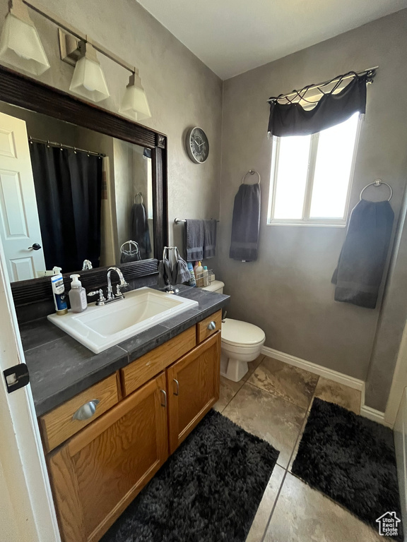 Bathroom with toilet, vanity, a shower with curtain, and baseboards