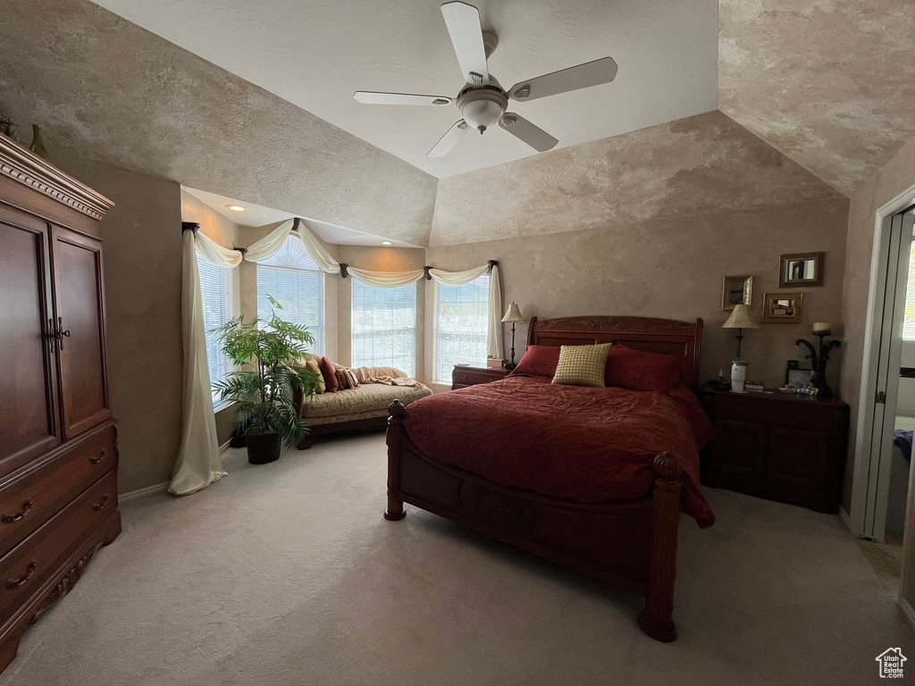 Bedroom with light colored carpet, lofted ceiling, and a ceiling fan