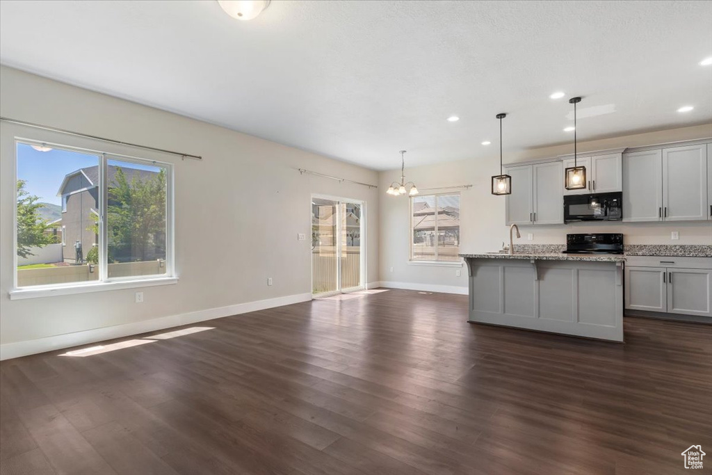 Kitchen featuring black microwave, stove, a chandelier, plenty of natural light, and recessed lighting
