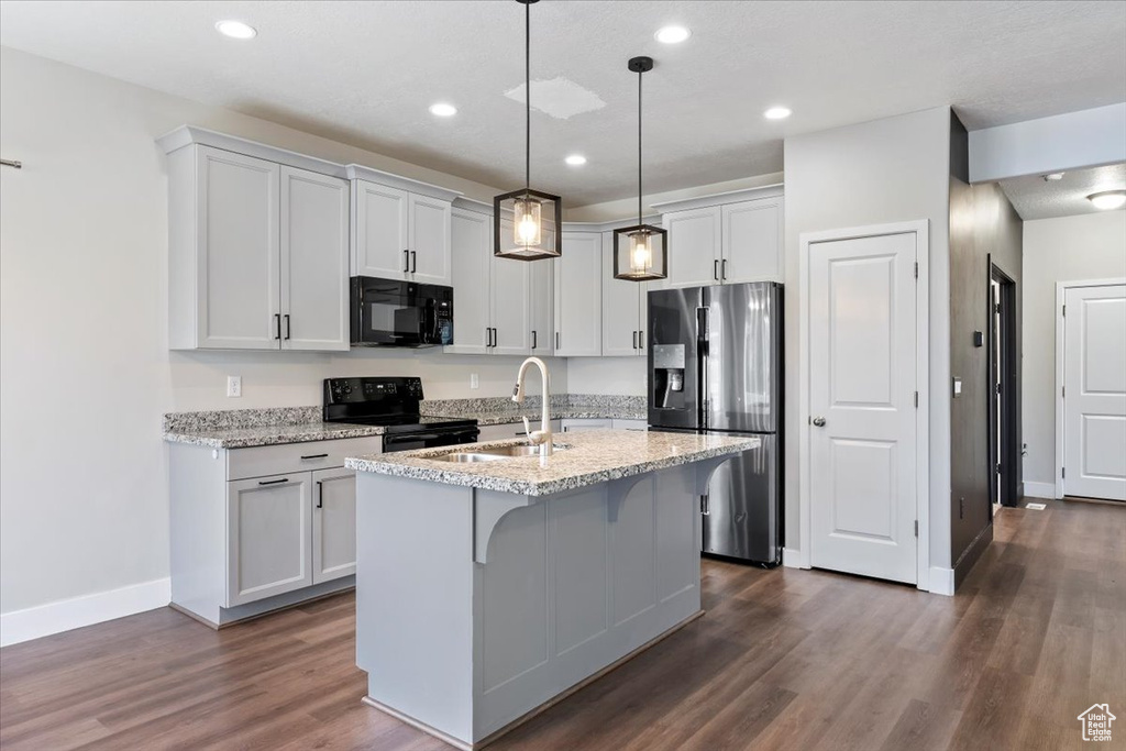 Kitchen with black appliances, a sink, baseboards, dark wood-style flooring, and an island with sink