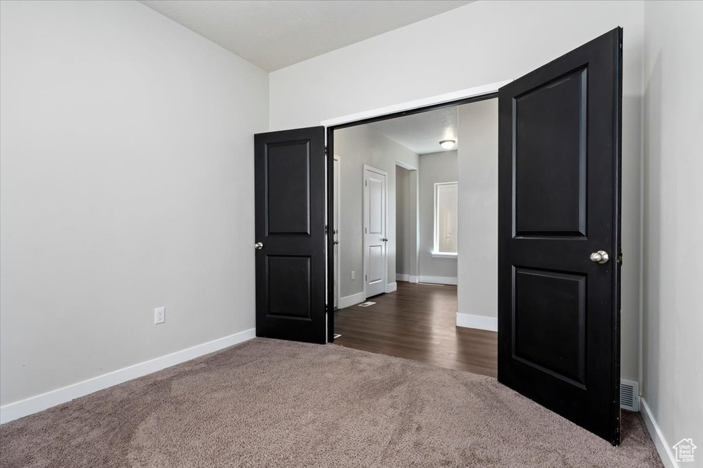 Unfurnished bedroom featuring dark colored carpet and baseboards