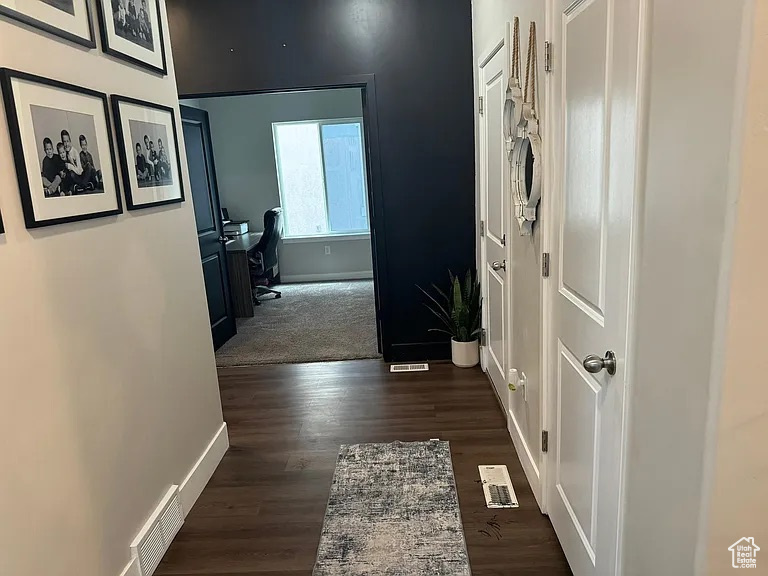 Hallway featuring baseboards, a desk, and dark wood finished floors