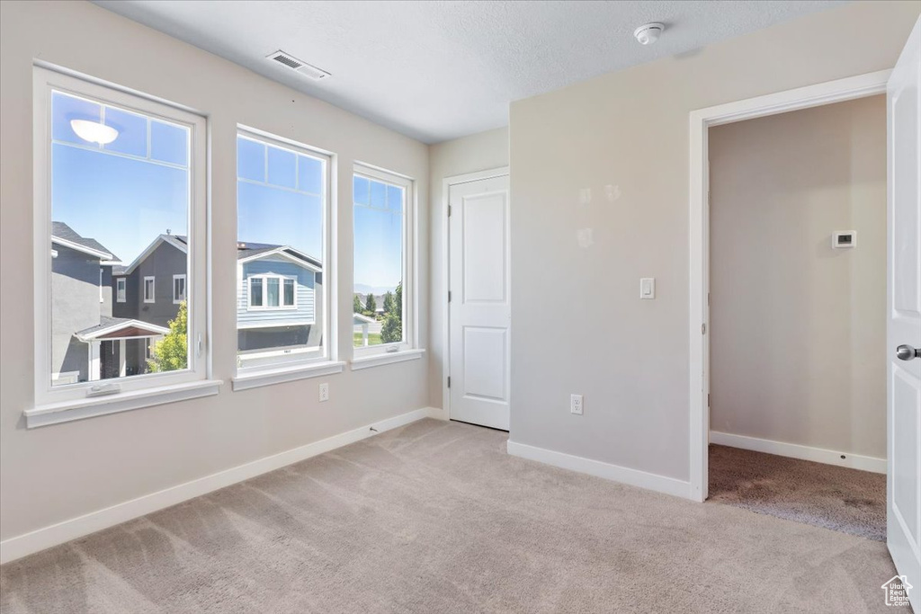 Carpeted spare room featuring baseboards and a smoke detector