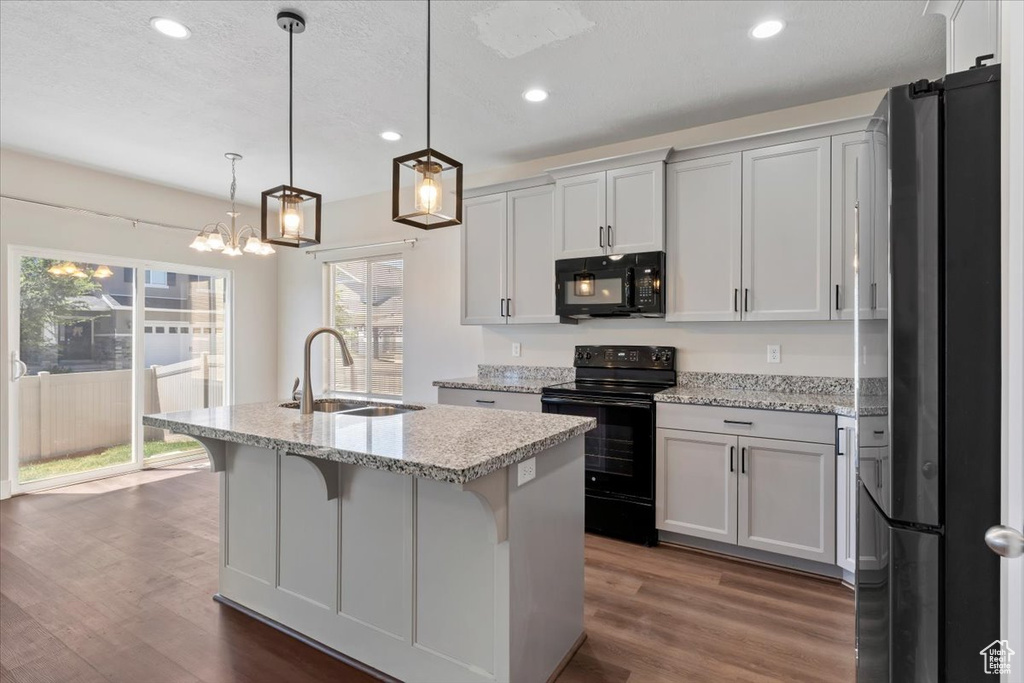 Kitchen featuring black appliances, a sink, dark wood-style floors, a center island with sink, and recessed lighting