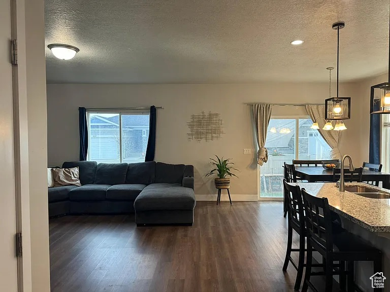 Living area with a textured ceiling, dark wood-style flooring, plenty of natural light, baseboards, and recessed lighting