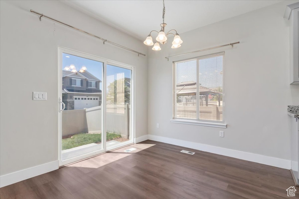 Unfurnished dining area featuring a chandelier, wood finished floors, and baseboards
