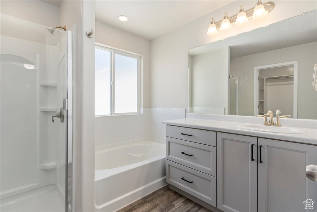 Full bathroom with a stall shower, vanity, a garden tub, and wood finished floors