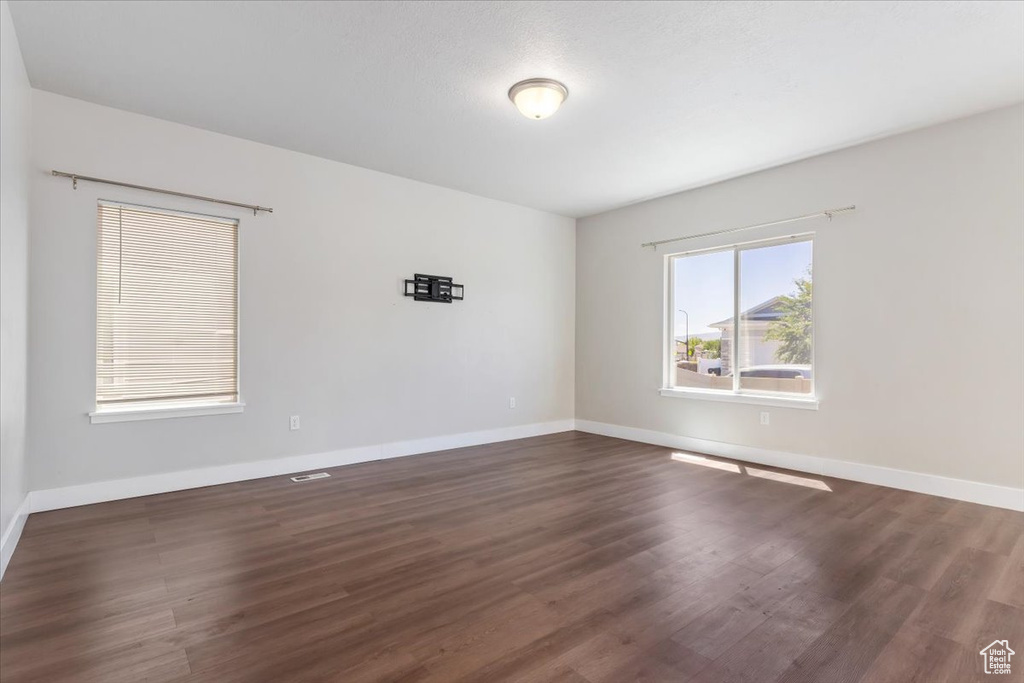 Spare room featuring baseboards and dark wood-type flooring