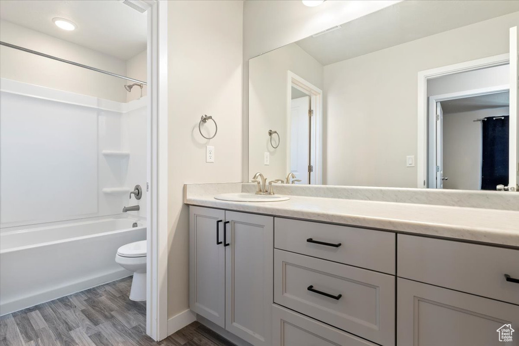 Bathroom featuring toilet, vanity, wood finished floors, tub / shower combination, and baseboards