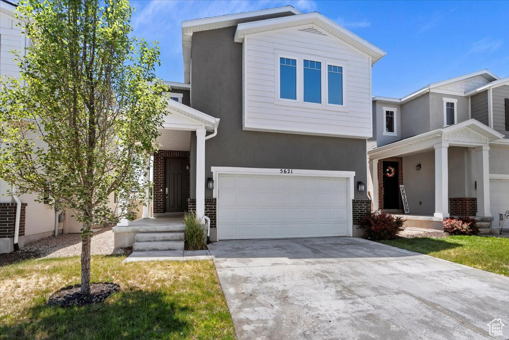 View of front of home featuring a garage, concrete driveway, and stucco siding