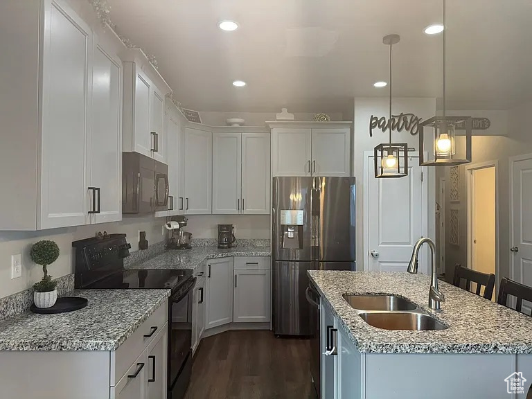 Kitchen featuring black appliances, a sink, a center island with sink, white cabinets, and dark wood finished floors