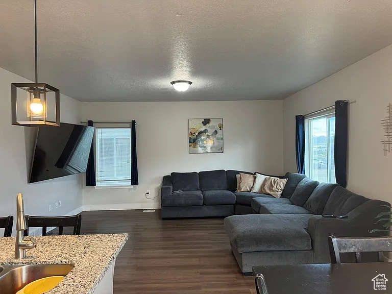 Living room featuring dark wood-type flooring, baseboards, and a textured ceiling