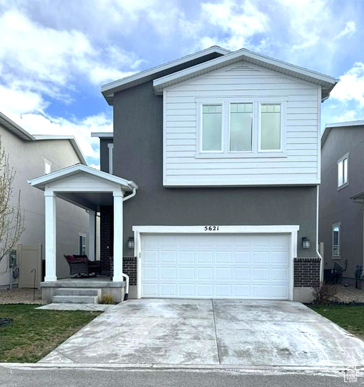 View of front of house with stucco siding, driveway, and a garage