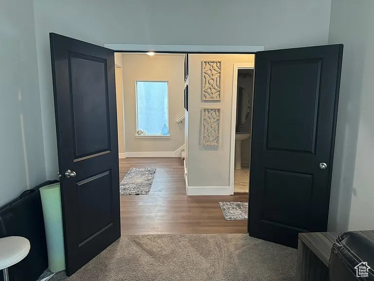 Hallway with baseboards, wood finished floors, and an upstairs landing