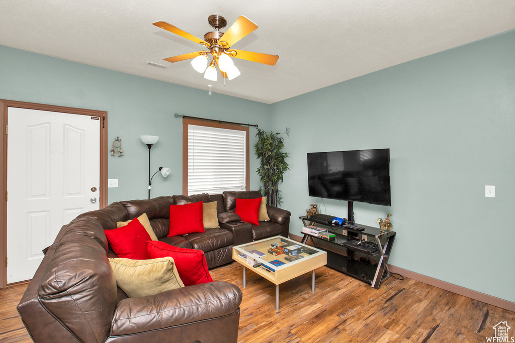 Living room with ceiling fan, wood finished floors, and baseboards