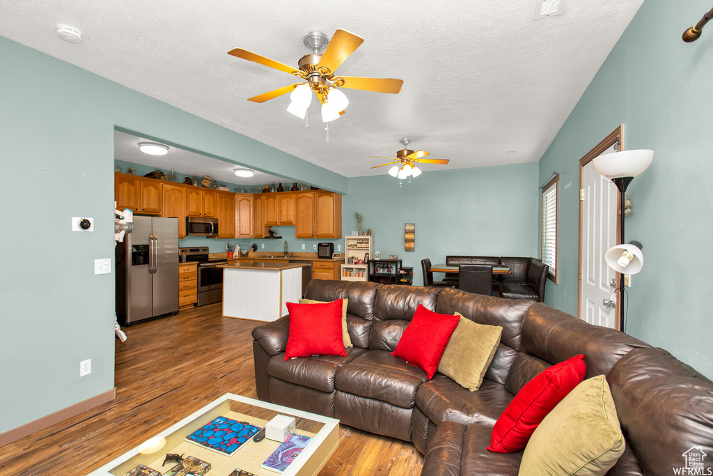 Living area featuring ceiling fan, wood finished floors, and a textured ceiling