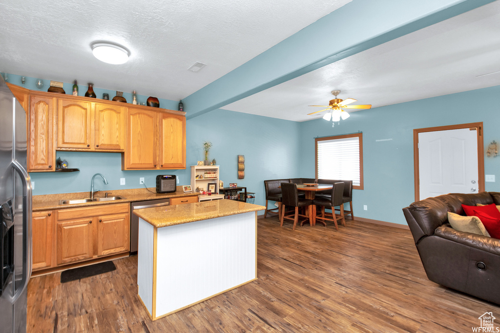 Kitchen with a sink, appliances with stainless steel finishes, dark wood finished floors, open floor plan, and a kitchen island