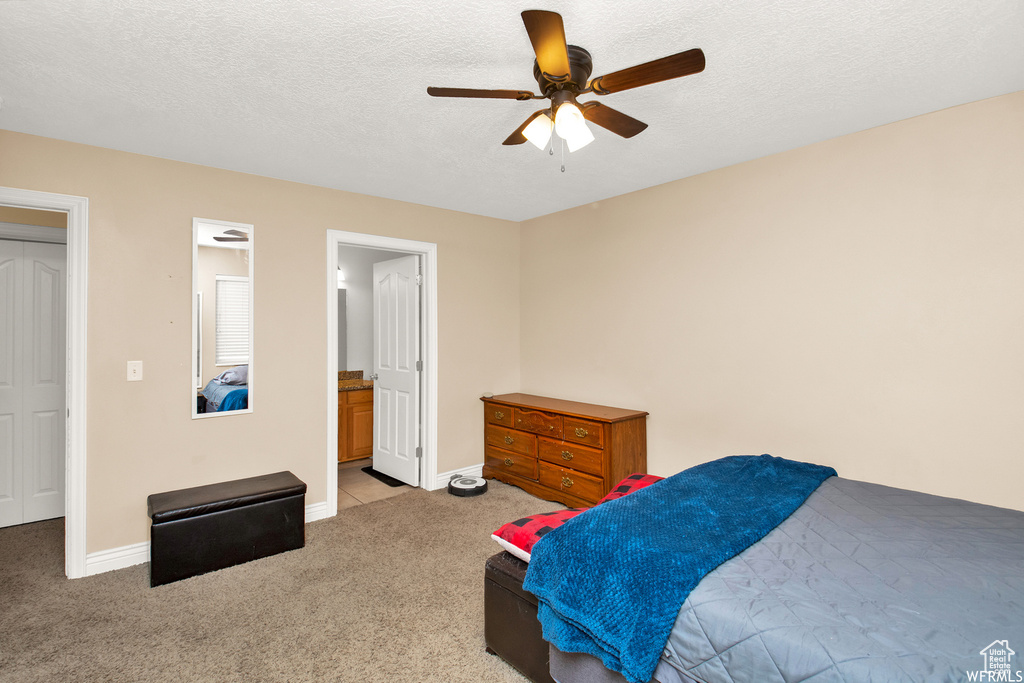 Bedroom with light carpet, baseboards, a textured ceiling, a ceiling fan, and ensuite bathroom