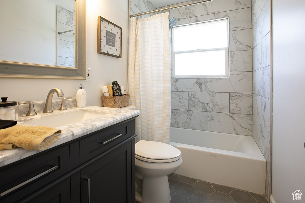 Bathroom featuring toilet, tile patterned floors, vanity, and shower / bath combo with shower curtain