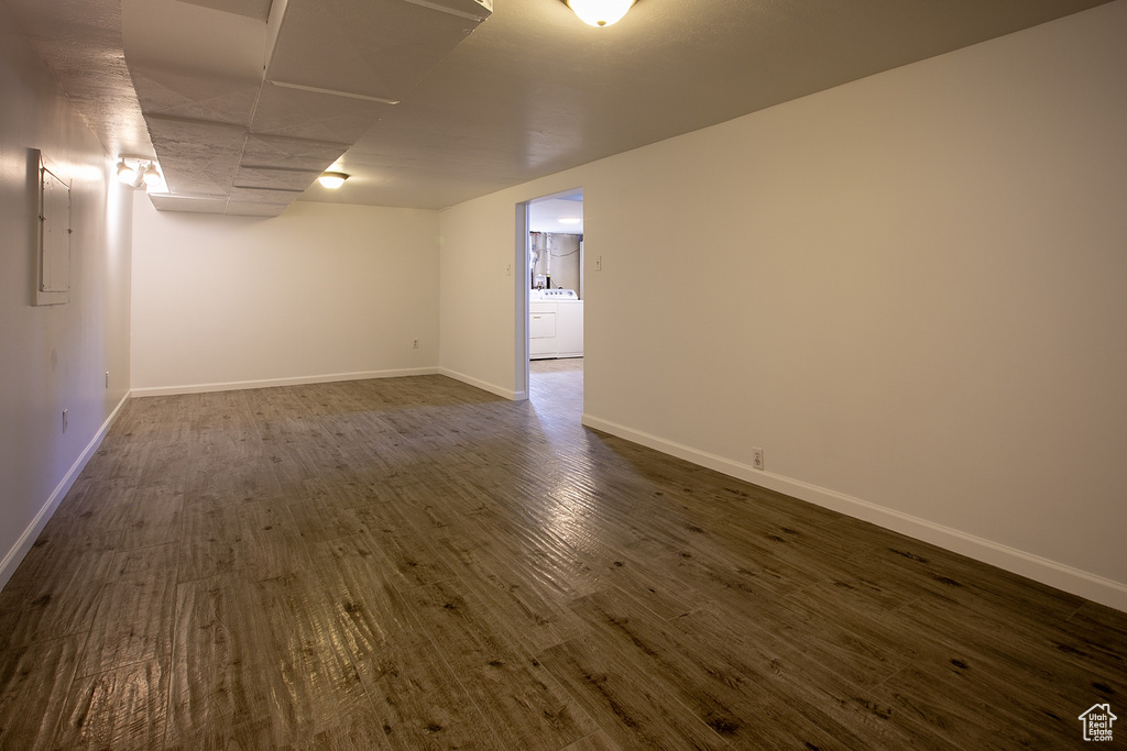 Finished below grade area with washer / dryer, dark wood-style floors, baseboards, and electric panel