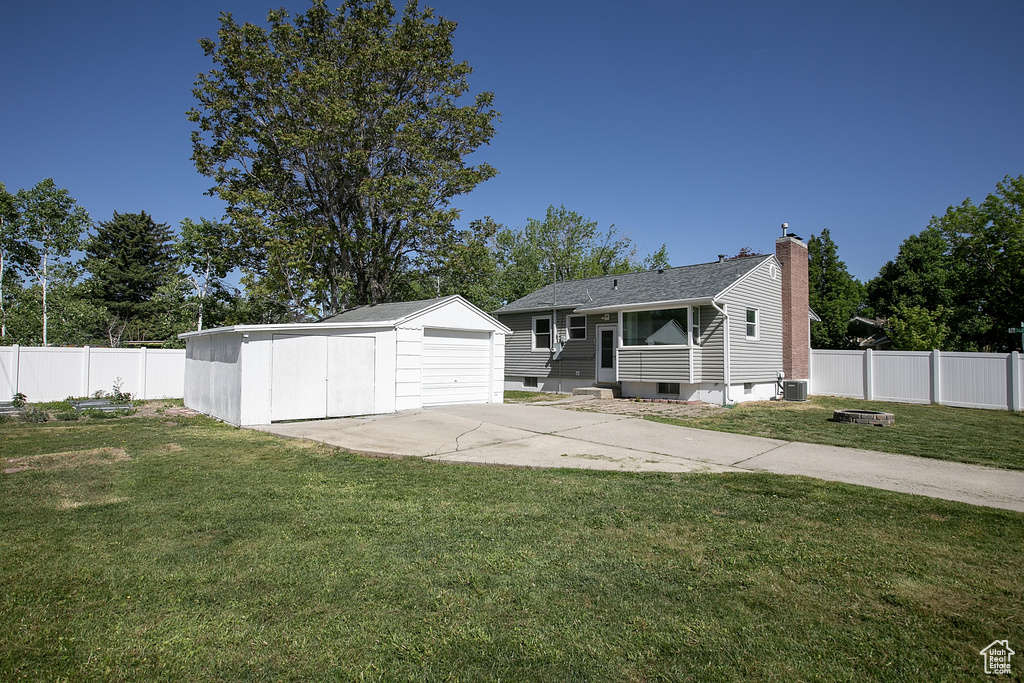 View of front facade with an outbuilding, central air condition unit, a chimney, a detached garage, and entry steps
