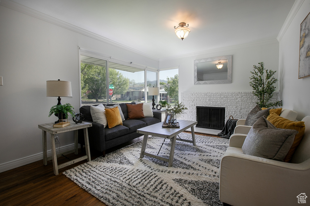 Living area with wood finished floors, a brick fireplace, crown molding, and baseboards