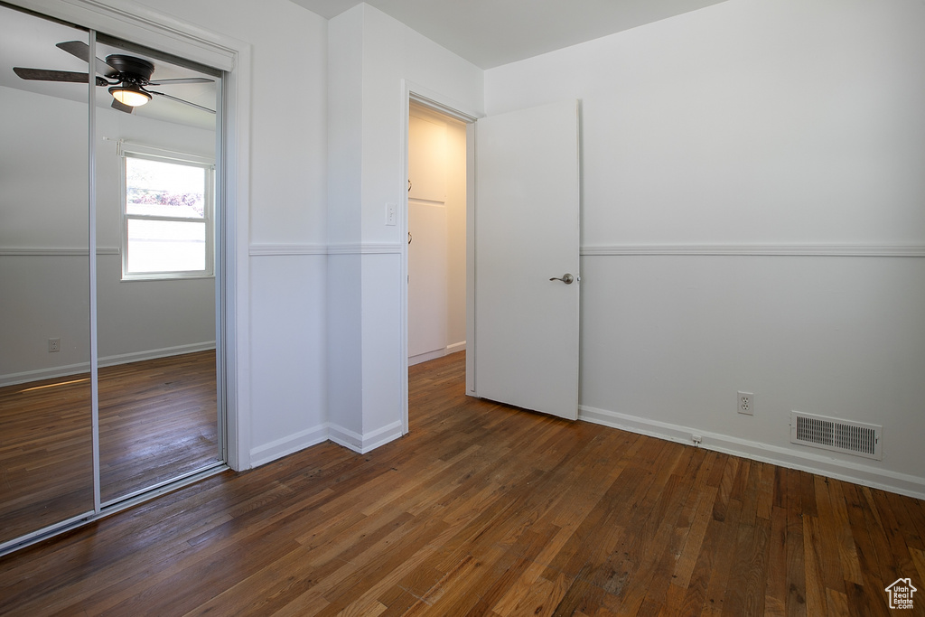 Unfurnished bedroom featuring a closet, wood finished floors, baseboards, and ceiling fan