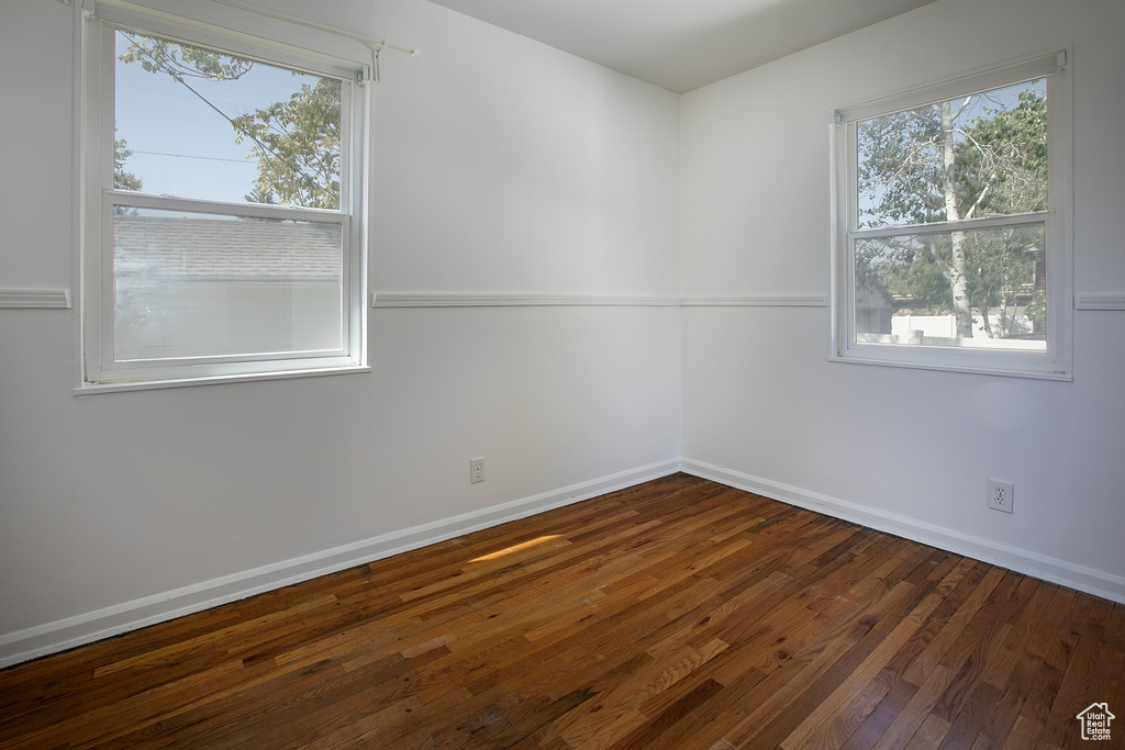 Spare room featuring dark wood finished floors, healthy amount of natural light, and baseboards