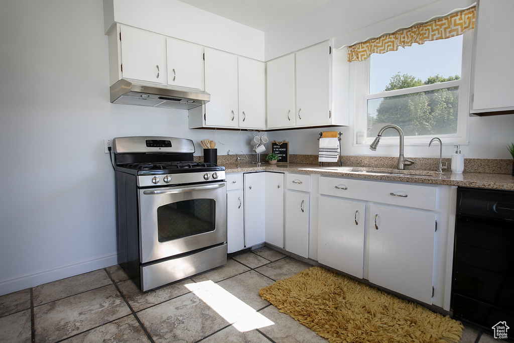 Kitchen with gas range, under cabinet range hood, a sink, baseboards, and white cabinets