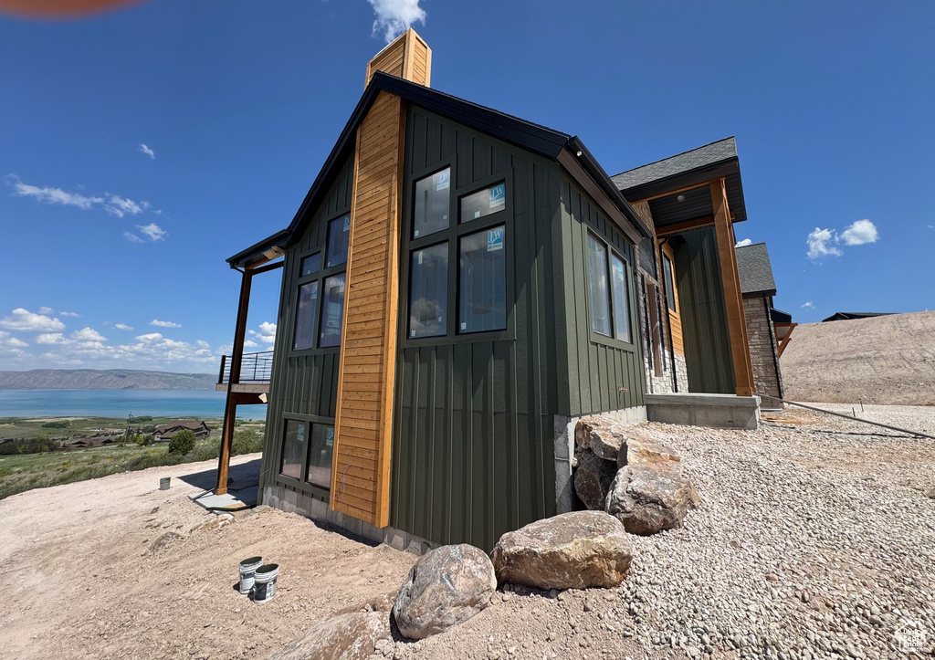 View of property exterior featuring a chimney, a water view, and board and batten siding