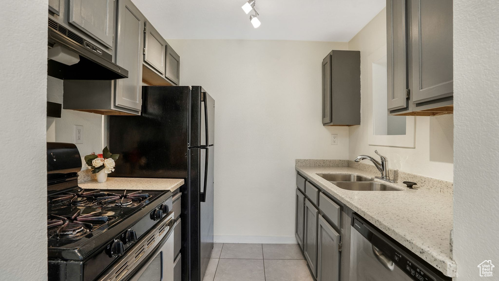 Kitchen featuring appliances with stainless steel finishes, under cabinet range hood, a sink, gray cabinets, and light tile patterned floors