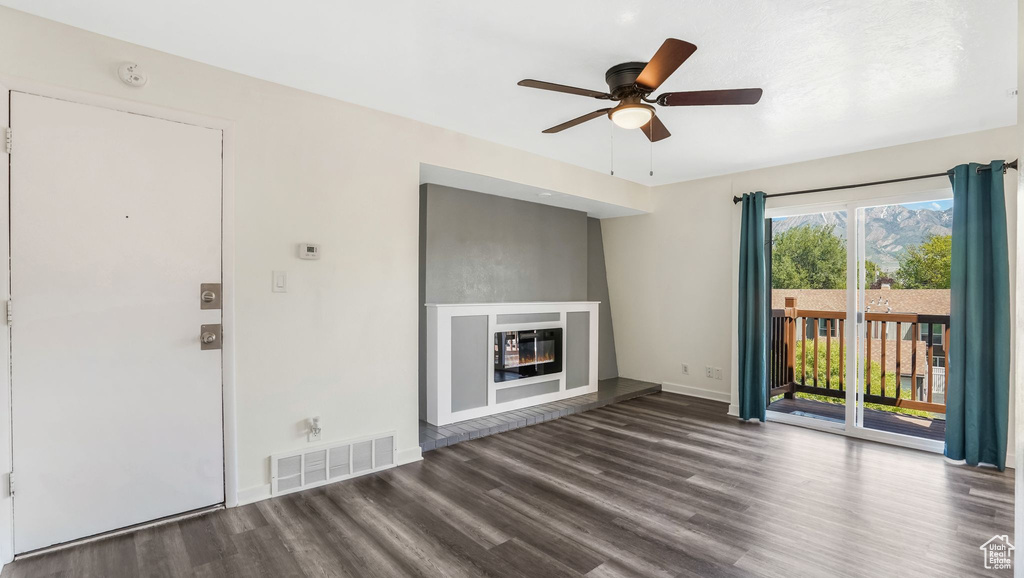 Unfurnished living room with wood finished floors, a ceiling fan, a glass covered fireplace, and baseboards