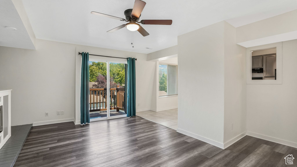 Unfurnished living room with a ceiling fan, wood finished floors, and baseboards