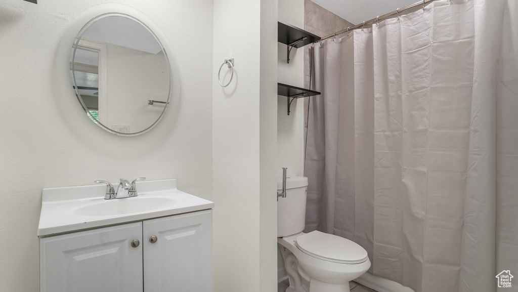 Full bath featuring toilet, vanity, and curtained shower