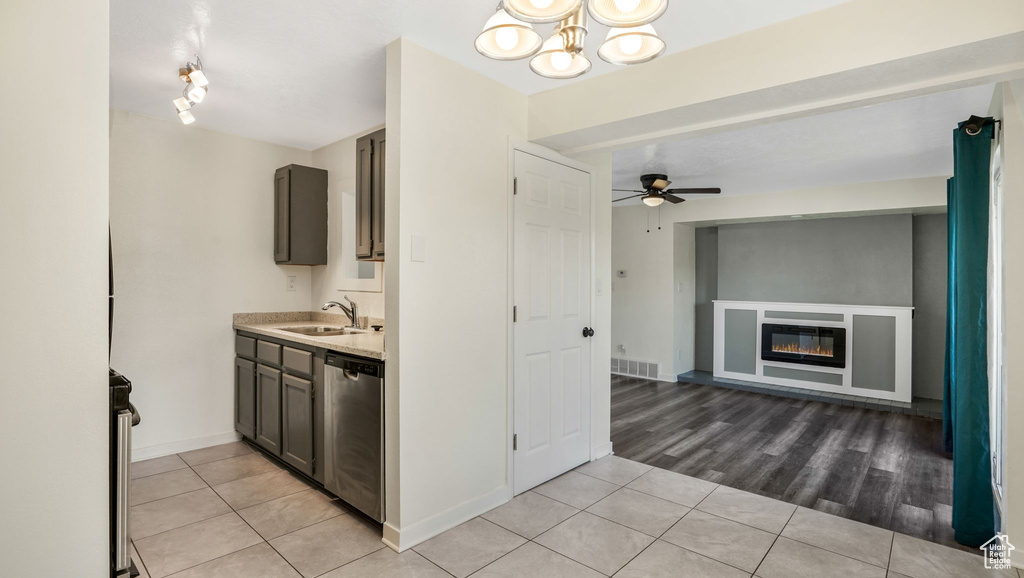 Kitchen with stainless steel dishwasher, light tile patterned floors, light countertops, and a sink
