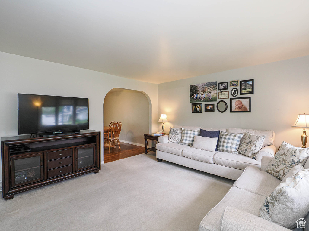 Living area with arched walkways, carpet, and baseboards