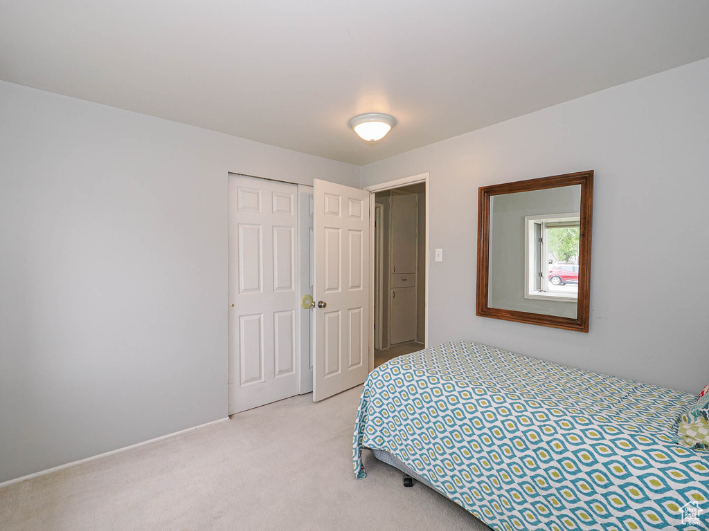 Bedroom featuring light carpet and a closet