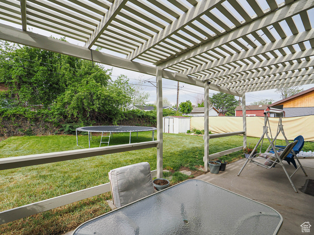 View of patio featuring a trampoline, a pergola, and outdoor dining area