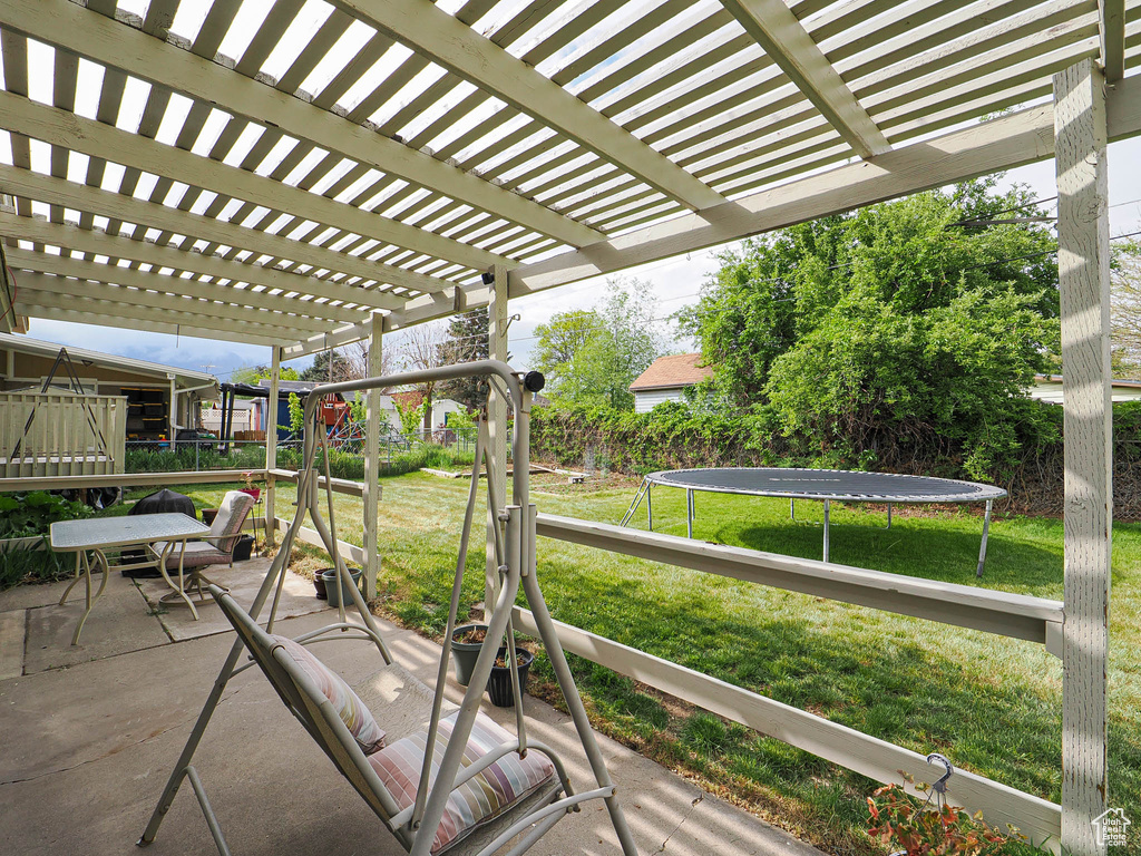 View of patio with a trampoline and a pergola