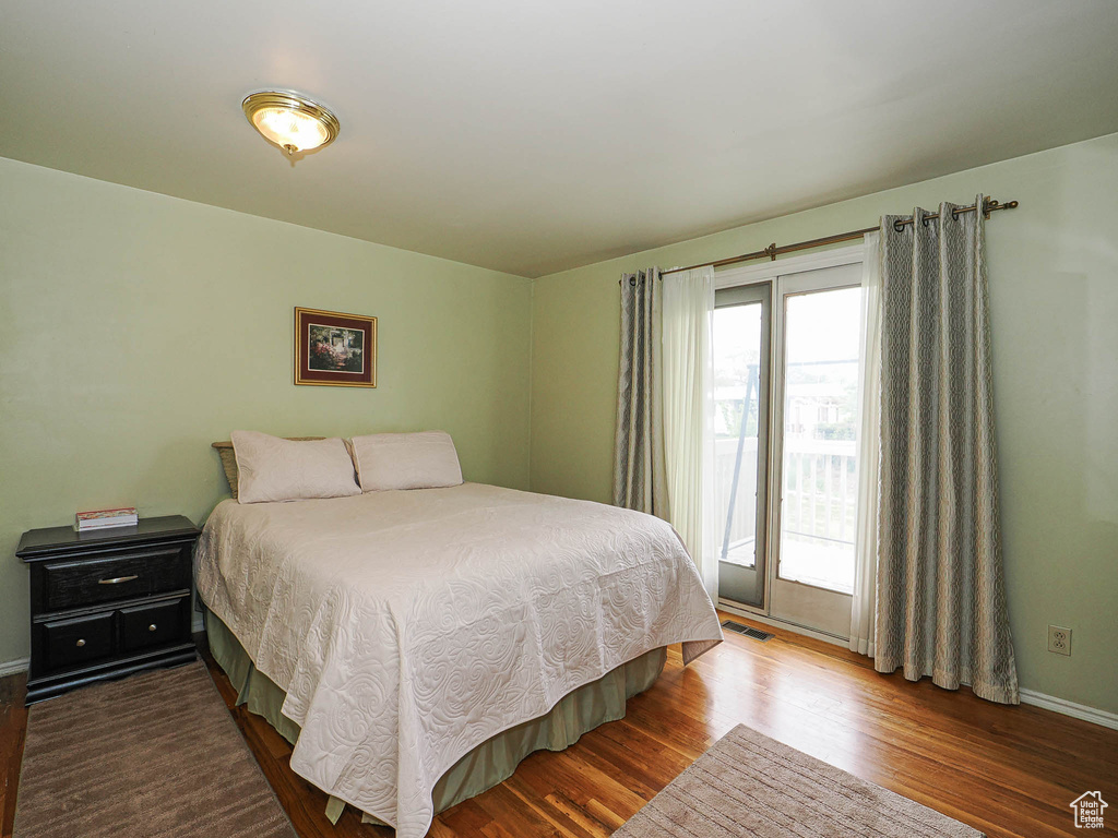 Bedroom with wood finished floors, baseboards, and access to exterior