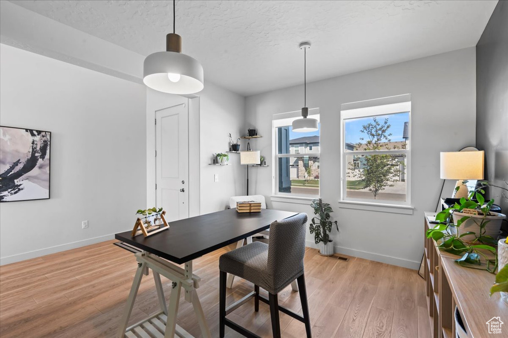 Dining space featuring light wood-style floors, baseboards, and a textured ceiling